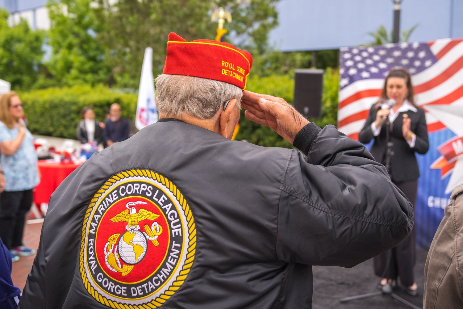 Veterán námořní pěchoty salutuje vlajce během a zpěvu Americké státní hymny